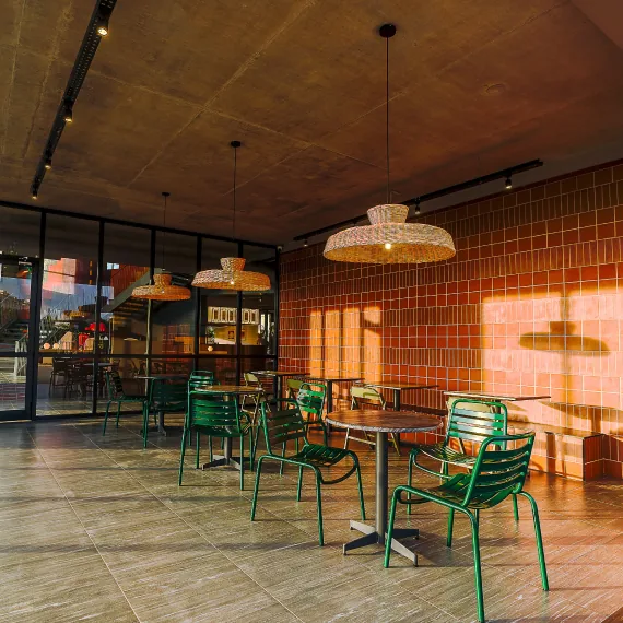 A clubhouse café with green chairs and a terracotta tiled wall at Orchid Piccadilly