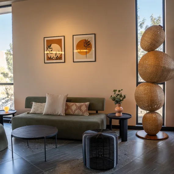 A clubhouse lounge with sofas, framed art and woven lamps at Orchid Piccadilly